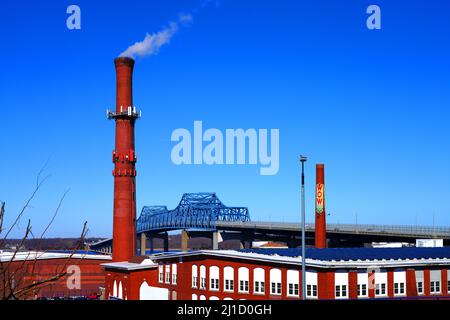 FALL RIVER, MA – 5. MÄRZ 2022 – Blick auf ein altes Ziegelgebäude der Industriefabrik und einen in einen Mobilfunkturm umgebauten Kamin in Fall River, Massachusetts Stockfoto