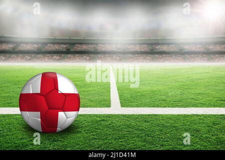 Fußball in einem hell erleuchteten Stadion im Freien mit einer bemalten Flagge Englands. Fokus auf Vordergrund und Fußball mit geringer Schärfentiefe auf Hintergrund A Stockfoto