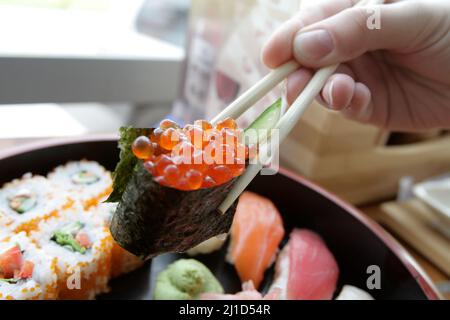 Eine Frau isst Gunkanmaki in einem japanischen Restaurant Stockfoto