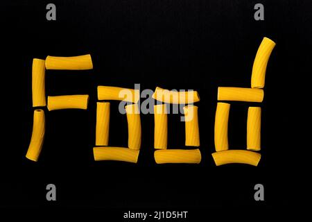 Italienische Hartweizenmaccaroni bilden das Wort Food auf schwarzem Hintergrund Stockfoto