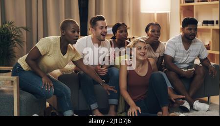 Dies ist ein großartiger Film, den man mit Freunden ansehen kann. Aufnahme einer Gruppe verschiedener Freunde, die sich zu Hause in der Lounge entspannen. Stockfoto