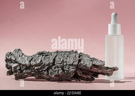 Serumöl mit Kollagen und Peptid in weißer transparenter Flasche mit Tropf auf rosafarbenem Hintergrund mit Rindenbaum. Hautpflege Schönheitsbehandlung medizinisch Stockfoto