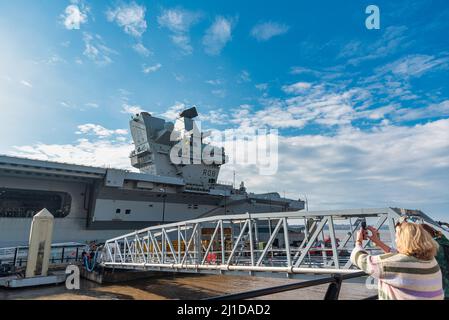 Liverpool, Großbritannien. 24. März 2022. Eine Frau fotografiert die Flugzeugträgerin HMS Queen Elizabeth, die an der City of Liverpool, Cruise Terminal am Fluss Mersey, anlegt. (Foto von Dave Rushen/SOPA Images/Sipa USA) Quelle: SIPA USA/Alamy Live News Stockfoto