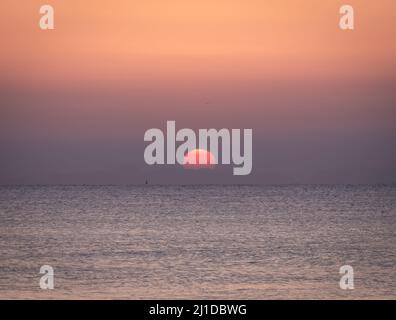 Sonnenaufgang am Strand mit ruhigem Meer Stockfoto