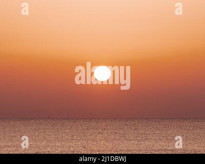 Sonnenaufgang am Strand mit ruhigem Meer Stockfoto