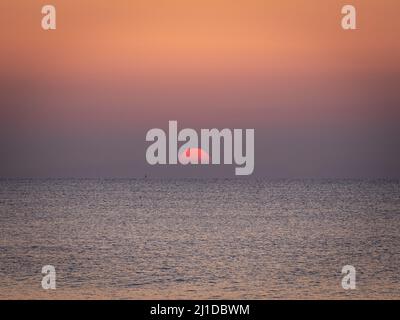 Sonnenaufgang am Strand mit ruhigem Meer Stockfoto