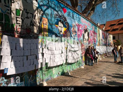 Prag, Tschechische Republik. 23. März 2022. Auf der sogenannten John-Lennon-Mauer in Prag hat ein Unbekannter den russischen Präsidenten Wladimir Putin angesichts des Ukraine-Krieges als Adolf Hitler dargestellt. Darüber auf Tschechisch steht der Slogan „valka je vul“ - wörtlich „Krieg ist ein Hornhund“. Was damit gemeint ist, ist, dass Krieg Unsinn ist. Die Lennon-Mauer auf der Prager Kleinseite ist seit dem Jahr 1980s mit sich ständig ändernden politischen Botschaften eingeschrieben. Es erinnert an den Beatles-Sänger John Lennon, einer der Ikonen der Friedensbewegung. Quelle: Michael Heitmann/dpa/Alamy Live News Stockfoto