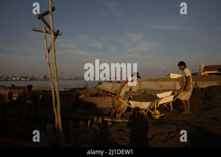 Arbeiter, die Sand am Ufer des Musi-Flusses in Palembang, Süd-Sumatra, Indonesien, entladen. Stockfoto