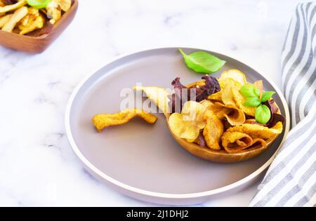 Vegane Snacks, bunte Gemüse- und Obstchips in Holzschüssel, selektiver Fokus. Schüssel mit gesunden Gemüsechips aus Rüben, Süßkartoffeln, ca. Stockfoto