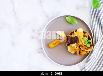 Vegane Snacks, bunte Gemüse- und Obstchips in Holzschüssel, selektiver Fokus. Schüssel mit gesunden Gemüsechips aus Rüben, Süßkartoffeln, ca. Stockfoto