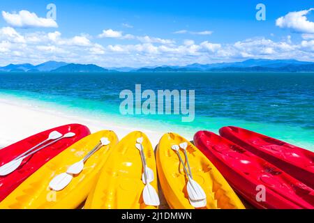 Farbenfrohe Kajaks auf einem tropischen Sandstrand an einem Sommertag, Inseln, blaues Meer, weiße Wolken am blauen Himmel im Hintergrund. Urlaub, Urlaub. Stockfoto