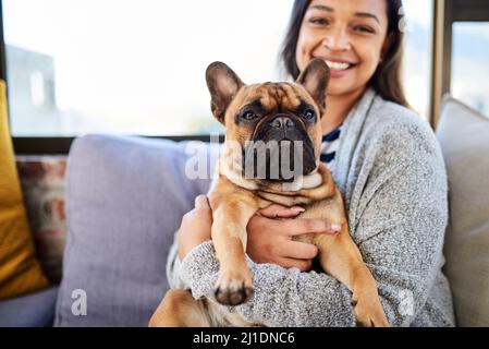 Ein Haus ist kein Zuhause ohne einen niedlichen Begleiter. Porträt einer jungen Frau, die sich zu Hause mit ihrem Hund entspannt. Stockfoto