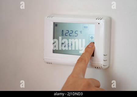 Energiesparen Konzept: Menschliche Hand Absenken der Temperatur auf dem Digitaldisplay Stockfoto