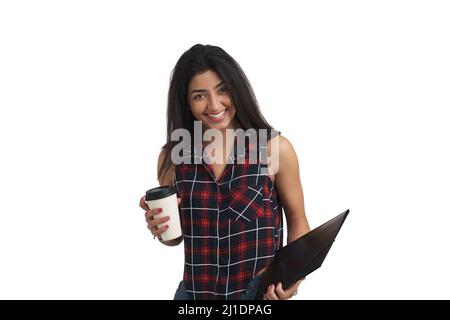 Junge Venezolanerin, die mit Kaffee und Ordner lächelt, isoliert. Stockfoto