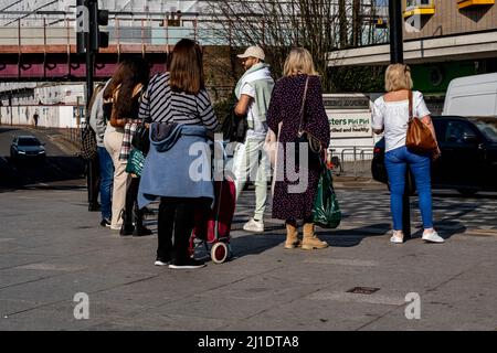 Kingston-upon-Thames, Kingston London, Großbritannien, 23 2022. März, Gruppe von Menschen, die stehen und plaudern, um eine Straße durch Ampeln zu überqueren Stockfoto