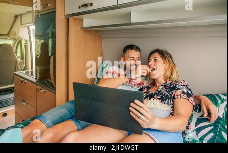 Mann füttert seine Freundin ein Popcorn und schaut sich einen Film auf dem Tablet in ihrem Wohnmobil an Stockfoto