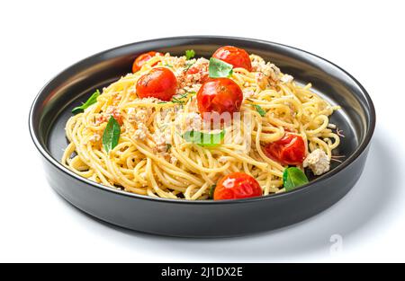 Pasta mit Feta, Kirschtomaten, Knoblauch und Basilikum auf einem schwarzen Teller ist auf weißem Hintergrund isoliert. Seitenansicht. Stockfoto
