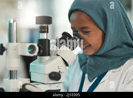 Durchführung fairer Tests. Aufnahme eines jungen Wissenschaftlers mit einem Mikroskop in einem Labor. Stockfoto