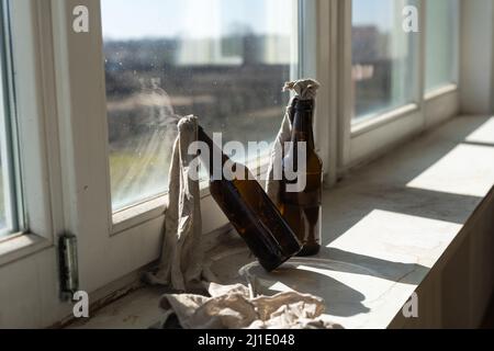 Glasflasche, gefüllt mit Benzin, einem sogenannten Molotow-Cocktail, auf dem Fenster im Haus Stockfoto