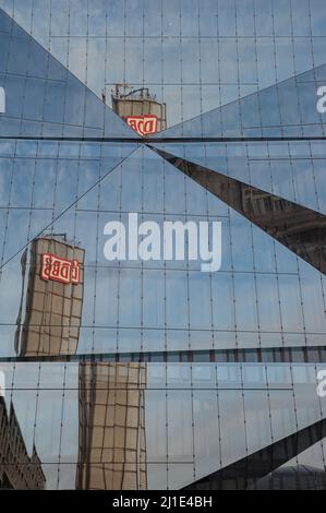 22.01.2022, Deutschland, , Berlin - der Turm des Berliner Hauptbahnhofs mit dem DB-Logo spiegelt sich in der futuristischen Glasfassade des neuen 3XN Cube B wider Stockfoto