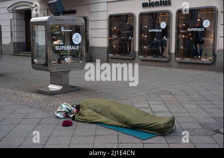 05.02.2022, Deutschland, , Berlin - Ein Obdachloser schläft in seinem Schlafsack auf dem Bürgersteig vor einem Modehaus am Kurfürstendamm. 0SL220205D00 Stockfoto