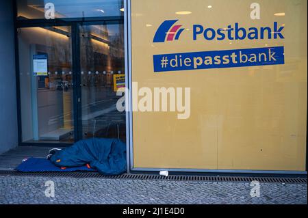 05.02.2022, Deutschland, , Berlin - Ein Obdachloser schläft in seinem Schlafsack auf dem Bürgersteig vor einer Postbank-Filiale in der Innenstadt. 0SL220205D Stockfoto