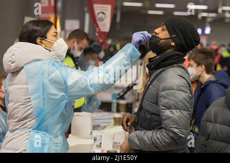 18.03.2022, Deutschland, Berlin, Berlin - Ukrainische Kriegsflüchtlinge, die mit dem Zug ankommen, werden am Hauptbahnhof von Freiwilligen betreut. Ein junger Mann bekommt Stockfoto