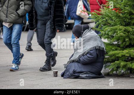 03.12.2021, Deutschland, Nordrhein-Westfalen, Essen - die Bettlerin sitzt während der Corona-Pandemie zu Weihnachten auf dem Bürgersteig in der Fußgängerzone Stockfoto