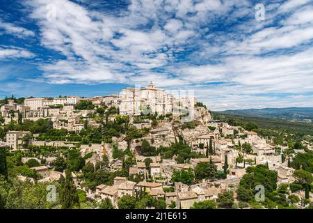 Eines der schönsten und berühmtesten Dorf Gordes am Fuße der Monts de Vaucluse gebaut, mit Blick auf den Luberon, unter einem bewölkten Himmel in einem sonnigen Stockfoto