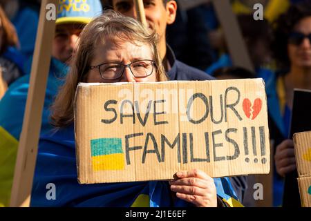 März 20. 2022. Hunderte Ukrainer und ihre Anhänger protestieren bei einer Kundgebung in Whitehall gegenüber der Downing Street, London, Großbritannien. Protest gegen den russischen Einmarsch in die Ukraine. Die Forderung nach einer NATO erzwang keine Flugzone über der Ukraine, militärische Hilfe, wirksame Sanktionen gegen Russland und humanitäre Hilfe. Aktivist drapiert in ukrainische Flagge mit dem Schild „Save Our Families“. Kredit: Stephen Bell/Alamy Stockfoto