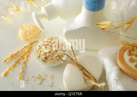 Duschprodukte mit Haferextrakt in Behältern mit Elementen für die persönliche Hygiene auf weißem Tisch. Erhöhte Ansicht. Horizontale Zusammensetzung. Stockfoto