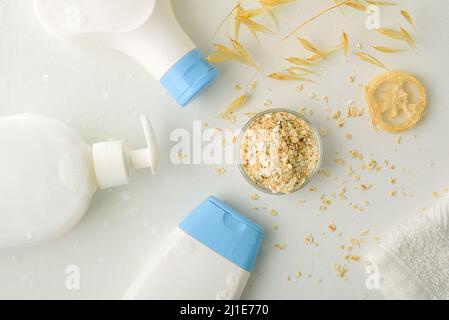 Detail von Badeprodukten mit Haferextrakt mit Trinkhalmen und Flocken auf weißem Tisch. Draufsicht. Horizontale Zusammensetzung. Stockfoto