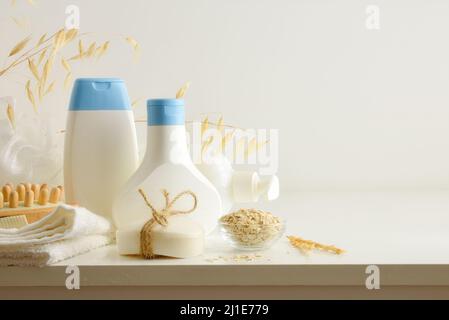 Duschprodukte mit Haferextrakt in Behältern mit Elementen für die persönliche Hygiene auf weißem Tisch. Erhöhte Ansicht. Horizontale Zusammensetzung. Stockfoto