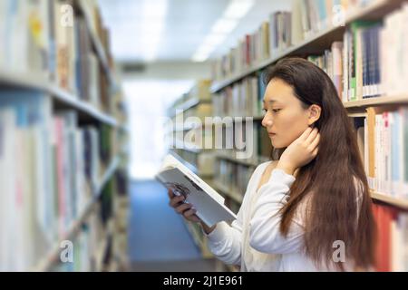 asiatische stilvolle junge Universität Schule Dame Forschung Student lesen Buch in der Bibliothek Stockfoto