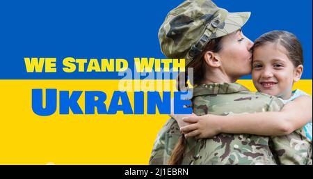 Wir stehen mit ukraine Text von kaukasischen Armee Mutter küssen lächelnde Tochter über Flagge Stockfoto