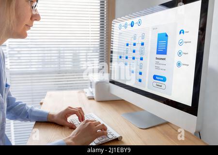 Dokumentenmanagementsystem (DMS), das effiziente Geschäftsprozesse ermöglicht. Frau, die mit dem Dateimanager auf dem Computerbildschirm im Büro arbeitet, um einen zu genehmigen Stockfoto