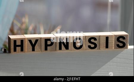 Hypnose-Wort auf Holzwürfel mit rotem Hintergrund geschrieben Stockfoto