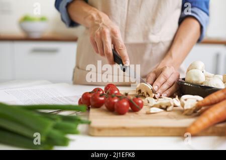 Die Anfänge von etwas köstlichem. Eine junge Frau hackt Gemüse. Stockfoto