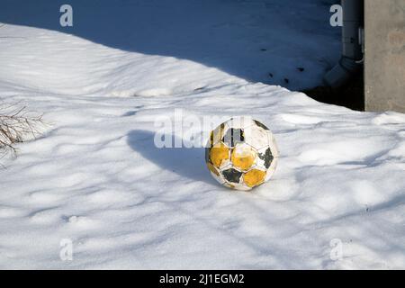 worn-out Fußball auf Schnee Stockfoto