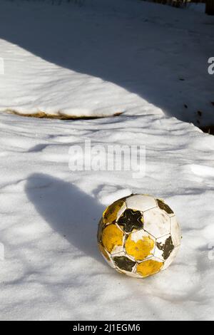 worn-out Fußball auf Schnee Stockfoto