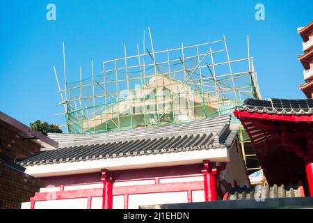 Bambusgerüste in Hongkong, China. Wunderschöne Aufnahme eines Originalgebäudes (chinesisches Tempeldach), Wartung, Renovierung. Baustelle Stockfoto