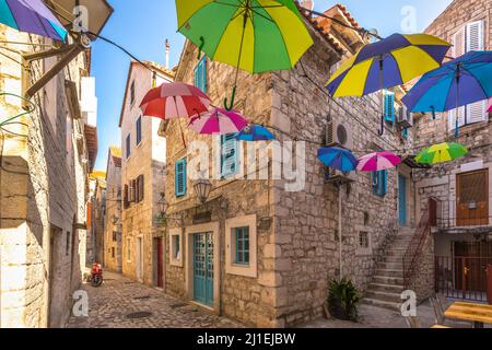 Bunte Regenschirme hängen in einer Steinstraße im historischen Zentrum von Trogir Stadt, Kroatien, Europa. Stockfoto