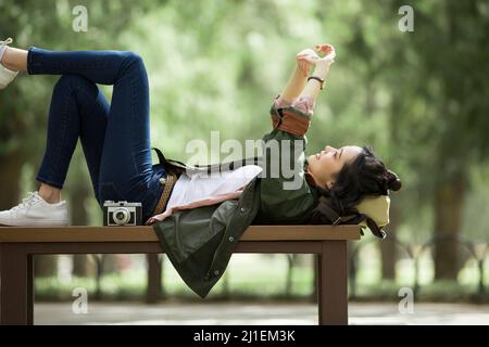 Junge Fotografin liegt und ruht auf der Bank - Stock Foto Stockfoto