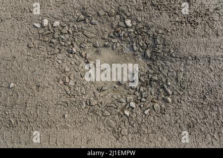 Bröckelnder Feldweg ohne Asphalt, aus Lehm und Schmutz mit Schutt, mit Gruben und Schlaglöchern gefüllt mit Wasser, Pfützen nass nach Regen Stockfoto