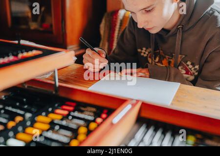 Mädchen Teenager-Künstler zeichnet auf Blatt Papier eine Zeichnung mit mehrfarbigen Buntstiften, konzentriert auf Zeichnung. Soft Focus Stockfoto