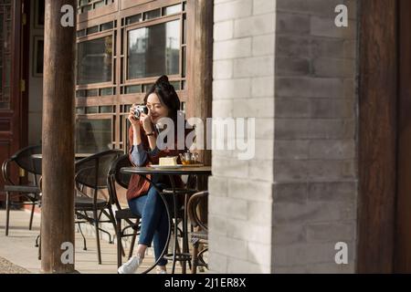 Junge Dame fotografiert im Straßencafé - Stock Foto Stockfoto