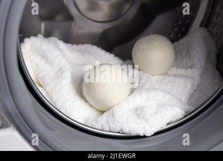 Verwendung von Wolltrocknerkugeln für mehr weiche Kleidung beim Trocknen im Wäschetrockner im Waschmaschinenkonzept. Entladen Sie statische Elektrizität und verkürzen Sie die Trocknungszeit. Stockfoto