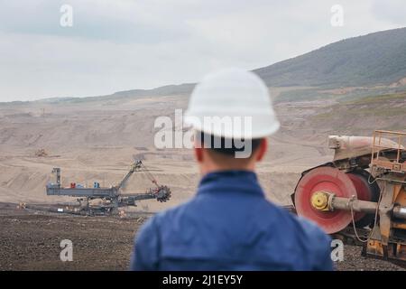 Kohlebergbau in Surface Mine. Bergmann beim Blick auf den riesigen Bagger. Stockfoto