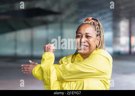 Ältere afrikanische Frau beim Stretching vor dem Laufen in der Stadt - Senioren Sportliche Menschen Lifestyle-Konzept Stockfoto