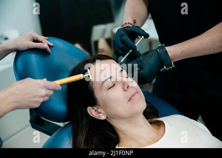 Nahaufnahme einer Frau, die Botulinumtoxin oder Füllstoffe auf Stirn und Gesicht bekommt Stockfoto